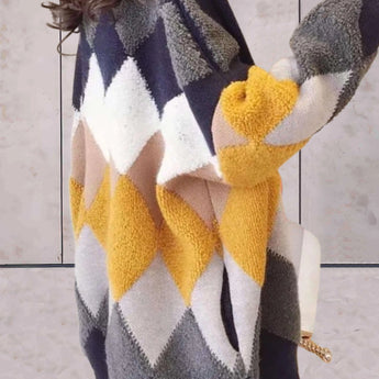 Women's oversized chunky knit cardigan sweater in a houndstooth pattern, in marine blue color, draped over a chair with visible long sleeves, highlighting its cozy and stylish texture and design.
