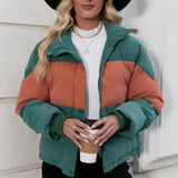 Women's oversized puffer jacket in green and orange color-block, shown in XL size, worn by a model accessorized with a hat and sunglasses.