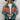 Women's oversized puffer jacket in green and orange color-block, shown in XL size, worn by a model accessorized with a hat and sunglasses.