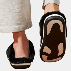 Women's cozy fleece-lined slippers in grey, featuring anti-skid soles, worn on a human foot.