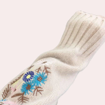 A woman wearing a cozy floral embroidered sweater, showcasing autumn winter fashion, with visible sleeves and a focus on comfort.