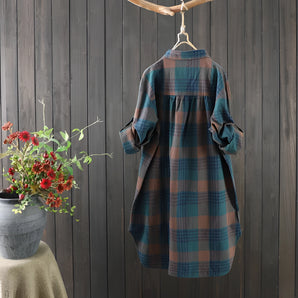 Women's cozy linen dress in a plaid pattern, vintage autumn style, midi length with sleeves, shown in a grey tartan print, surrounded by flowers and plants.