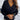 
A woman wearing a black women's deep V-neck button cuff sweater in size XXL. The sweater is styled for both office and casual settings.