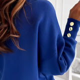 A woman wearing a deep V-neck sweater with button cuffs, styled with jeans. The sweater is a cozy knit suitable for office or casual settings, showcasing long sleeves and a comfortable fit.