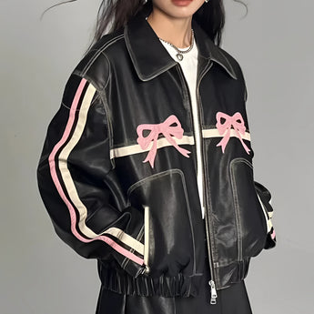 Women's designer leather jacket featuring a bow motif and metallic stripes, predominantly white with black accents, showcasing a stylish design with a structured collar, defined waist, and long sleeves, emphasizing modern fashion elements.