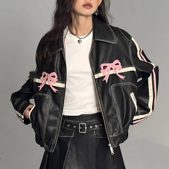 Black women's designer leather jacket featuring a pink bow motif and metallic stripes. The jacket has a stylish collar and shoulder design, with long sleeves. Fashionable and cool, it is paired with black hair, highlighting its chic appearance.