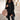A woman wearing a chic black double-breasted long winter coat, featuring a tailored fit with prominent shoulders, a stylish collar, and full-length sleeves. The coat is complemented by casual accessories and is marked as a 5XL size, showcasing an urban fashion style.