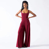
A woman wearing an elegant red sleeveless wide-leg jumpsuit in a formal style.