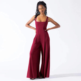 
A woman wearing an elegant red sleeveless wide-leg jumpsuit in a formal style.