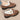 Women's faux fur-lined suede loafers in brown, featuring a bow tie design and moccasin style on a beige and grey wooden background.