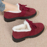 Women's red faux fur-lined suede loafers with bow tie detailing on top, shown with a human leg for scale.