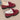 Women's red faux fur-lined suede loafers with bow tie detailing on top, shown with a human leg for scale.