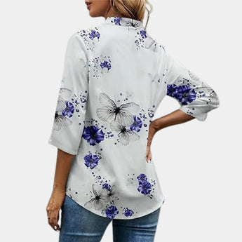 Women's floral blouse with 3/4 sleeves featuring a V-neck design, primarily in white with purple floral patterns.