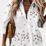 Elegant women's floral blouse featuring a V-neck design with 3/4 sleeves, predominantly in white with purple floral patterns. This blouse is styled in a beige color and is available in a 2XL size, showcasing a fashionable and sophisticated look.