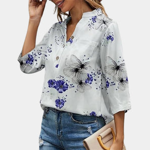
A women's floral blouse featuring 3/4 sleeves and a V-neck design, in elegant white and purple colors.