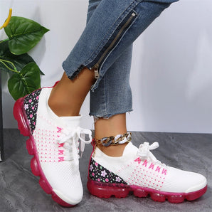 Women's floral mesh sneakers featuring a pink sole, designed for lightweight and breathable comfort, shown on a model's foot.
