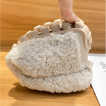 Women's fluffy slippers on a wooden floor, showcasing their plush texture and non-slip sole designed for warmth and comfort during winter.