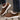 Women's brown fleece-lined winter loafers on a person's feet, styled with blue jeans; the loafers are warm slip-ons suitable for cold weather.