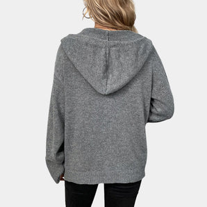Women's gray knit oversized hoodie showcasing comfortable urban fashion with prominent arm and shoulder details, featuring a woolen texture and a cozy collar design.