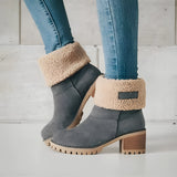 A pair of women's green suede shearling block heel ankle boots, shown worn on a model with denim jeans and visible human legs.