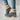 A pair of women's green suede shearling block heel ankle boots, shown worn on a model with denim jeans and visible human legs.