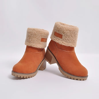 Women's green suede shearling block heel ankle boots on a model's legs. The boots feature a plush shearling lining and a sturdy block heel, providing both style and comfort. The suede material gives a luxurious feel, while the green color adds a pop of color to the outfit.