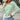 
A woman wearing a green and white striped boat neck sweater, designed for casual spring fashion, standing confidently. The sweater features long sleeves and a comfortable fit, suitable for an XL size.