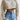 Women's grey cropped cable knit wool sweater styled with jeans, highlighting the shoulder and neck details, featuring long sleeves perfect for winter fashion.