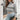 Women's grey cropped turtleneck Aztec sweater displayed, highlighting modern knitwear design with distinct Aztec patterns; the image captures the upper body section, emphasizing the sweater's fit around the shoulders and neck area.