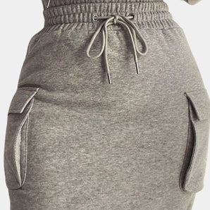 Women's grey joggers with a sporty design, featuring a drawstring waist and side pockets, displayed on a flat surface.
