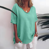 A woman wearing a loose, short sleeve, V-neck grey linen tunic blouse, styled casually for summer.
