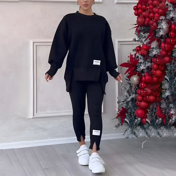Women's grey loungewear set, featuring a stylish and comfortable sweatshirt and pants. The set is in Nero color and size 3XL. The image shows a full body shot of the loungewear, highlighting the sleeves, waist, and leg areas. The model is standing, showcasing the fit and style of the clothing.