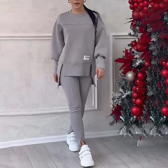 Women's grey loungewear set featuring a stylish and comfortable sweatshirt with long sleeves and matching pants. The set is displayed in a fashion-forward design, with a focus on casual elegance and comfort.
