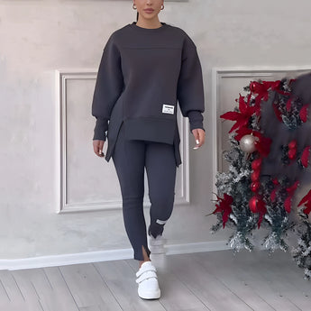 Women's grey loungewear set featuring a stylish sweatshirt with long sleeves and matching comfortable pants, designed for a relaxed fit. The set is perfect for standing and lounging, capturing a chic and cozy look.