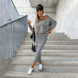
A woman smiling while standing on stairs, wearing a grey midi skirt and a cold-shoulder top, complemented by sporty sneakers and a cap. She is posing for a flash photograph, showcasing the outfit in a 2XL size.
