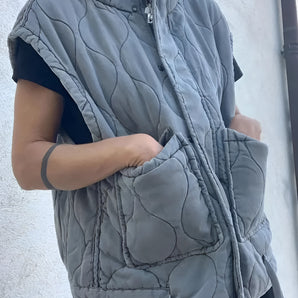 Women's grey sleeveless quilted puffer vest with a high collar, designed for lightweight winter layering.