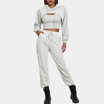 Women's grey tracksuit set featuring a cropped hoodie with long sleeves and a pair of joggers, designed for urban athleisure. The set is styled in a casual yet fashionable manner, suitable for everyday wear. The fabric appears soft and comfortable, with a focus on a sleek, modern look.