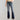 Women's high-waist dark wash flared stretch jeans in marine blue displayed, showcasing the waist, thigh, and knee areas. The jeans are paired with a leather jacket, emphasizing the denim texture and fit.