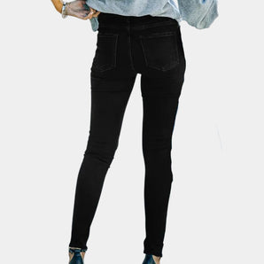 Women's high-waisted stretchable black skinny jeans, slim fit, modeled on a person standing, showcasing the fit around the legs and waist.