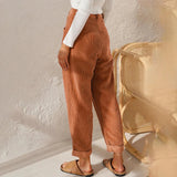Women's high-waisted terracotta corduroy cropped pants worn by a model, showcasing the pants' fit around the waist and thighs, with the hem falling above the ankles. The model is paired with a blazer and dress shirt, emphasizing a chic and stylish outfit.