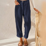 
A woman wearing high-waisted terracotta corduroy cropped pants, styled with a dark blue top. The pants feature a fashionable and comfortable fit, showcasing the waist and thighs. The woman is standing and gesturing, emphasizing the stylish and casual look.