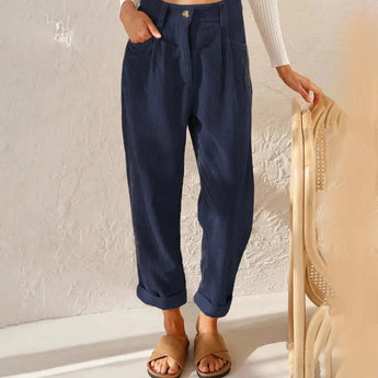 
A woman wearing high-waisted terracotta corduroy cropped pants, styled with a dark blue top. The pants feature a fashionable and comfortable fit, showcasing the waist and thighs. The woman is standing and gesturing, emphasizing the stylish and casual look.
