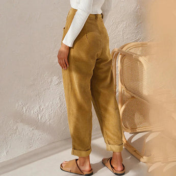 Women's high-waisted terracotta corduroy cropped pants displayed on a model, showcasing the waist, knee, and thigh areas with a casual fashion design. The model is wearing a beige blazer to complement the pants, highlighting a stylish outfit choice.