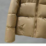 Women's hooded color block insulated puffer jacket displayed on a beige outdoor leather couch, showcasing the jacket's stylish design and comfortable fit.