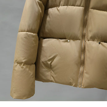 Women's hooded color block insulated puffer jacket displayed on a beige outdoor leather couch, showcasing the jacket's stylish design and comfortable fit.