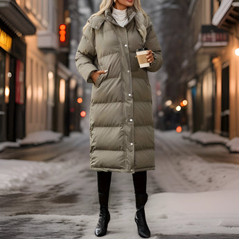 
A woman wearing a long down winter coat with a hood, designed to keep warm in snowy, freezing conditions. The coat has a fitted waist, extends to the knees, and features fur detailing around the hood.