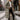Olive green women's insulated puffer coat in 3XL size, featuring a long design with a hood, suitable for winter. The coat has a stylish overcoat look with a waist belt and fur-lined hood, set in a snowy outdoor scene.