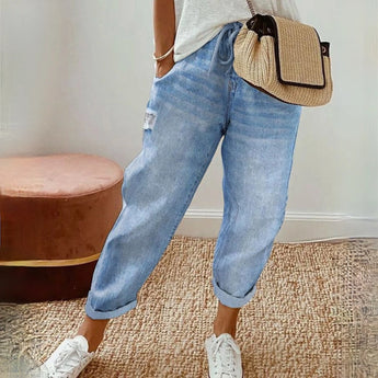 
A pair of women's lightweight denim jeans in washed blue, featuring a relaxed fit with a cropped length, displayed against a plain background. The focus is on the waist, thigh, and knee areas, highlighting the fabric's texture and stitching details.
