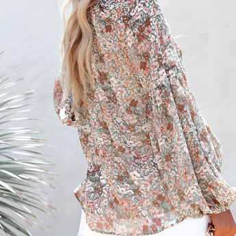 Women's lightweight floral V-neck blouse with a boho chic design, featuring long sleeves and a vibrant floral pattern. The blouse is styled for a fashionable and relaxed spring look, worn by a model showcasing its elegant fit at the waist and thigh.