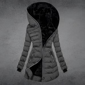 Women's long black puffer coat with an asymmetric front zip and oversized hood, shown in a gray color variant. The coat is styled with a loose fit and features long sleeves.